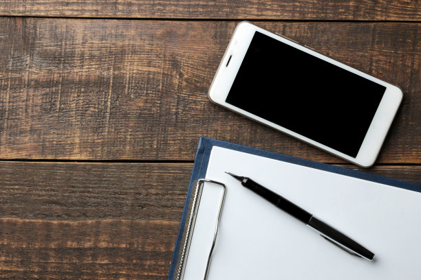 智能手机白色和空白的铭文在一个棕色的木桌上。从上面的观点图片下载