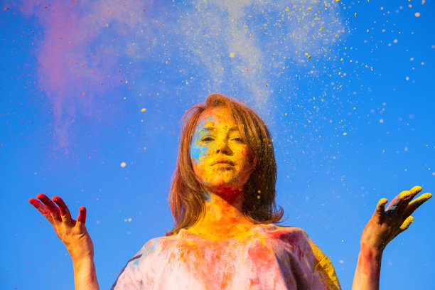 在蓝天的映衬下，女人满身洒满了胡里节粉。胡里节色彩的节日。图片下载