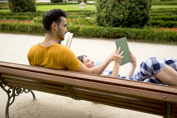 在公园里，一对悠闲的情侣后面看书图片下载