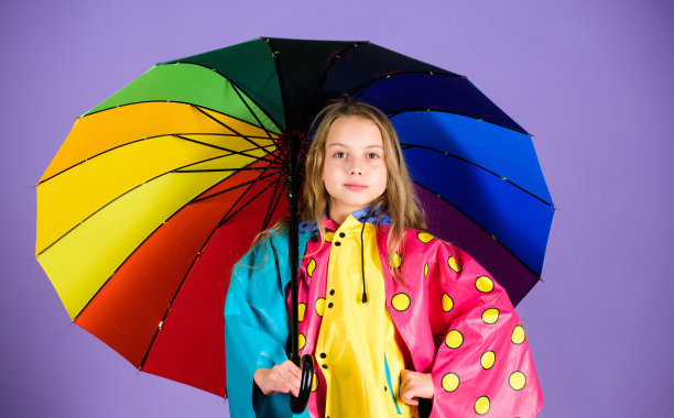 防水配件，雨天愉快愉快。小朋友女孩开心的撑着五颜六色的伞穿防水斗篷。儿童防水配件。穿着合适的衣服享受雨天图片下载