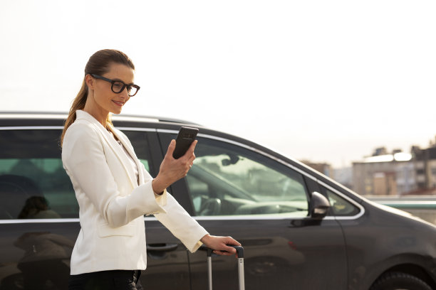 女商人带着行李走向停车的汽车。图片下载