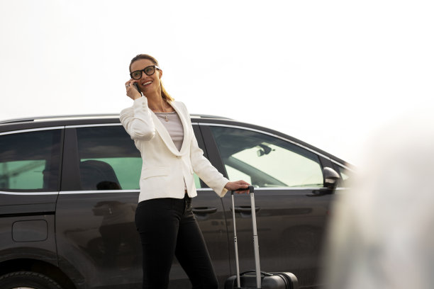 女商人带着行李走向停车的汽车。图片下载