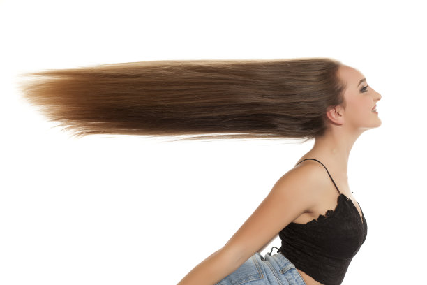 年轻微笑的女人与很长飞扬的头发在白色的背景图片下载