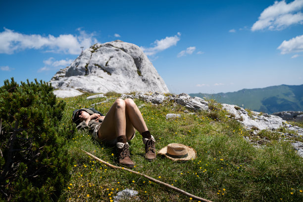 年轻的白人妇女躺在草地上休息，在蓝天白云之上图片下载