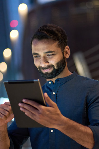 夜晚城市户外使用平板电脑的印度商人（竖版）图片下载