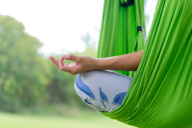 在反重力瑜伽吊床上做冥想姿势的女人特写。空中瑜伽的概念图片下载