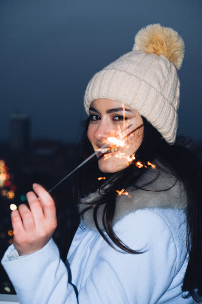 年轻美丽的女人与一个冬季的帽子拿着洒水器和微笑图片下载