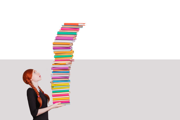 回到学校。聪明的红发女学生拿着一叠书。惊讶的脸。浅色背景上的彩色书籍图片下载