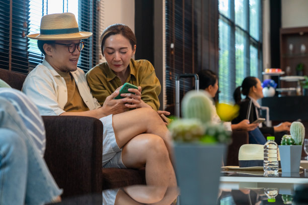 亚洲夫妇在机场候机楼的机场私人休息室使用手机。图片下载