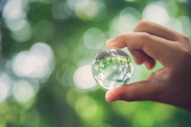 在生态环境森林的绿色自然背景下，人类手握地球球体水晶或可持续地球玻璃。节约环境理念，保护地球。图片下载