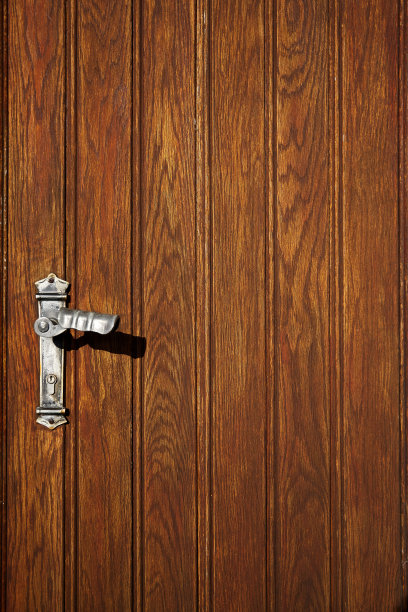 木门上带锁孔的铬合金把手。入口。建筑细节特写照片。内部碎片作为几何背景。图片下载