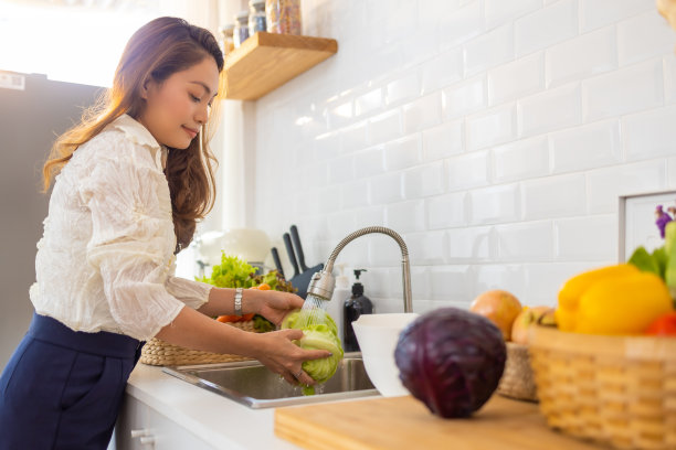 亚洲妇女在厨房水槽里洗蔬菜图片下载