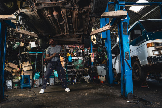 汽车悬挂专家正在仔细检查损坏的汽车。图片下载