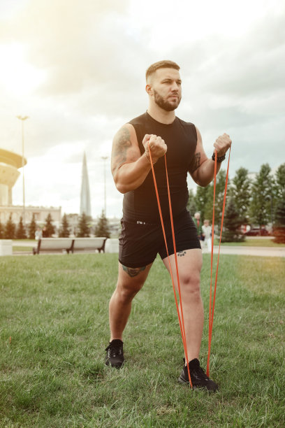 运动员帅哥运动员在城市公园户外用阻力带做弓步锻炼。健身健康的生活方式理念配合男性运动员，用橡皮筋锻炼。复制文本空间图片下载