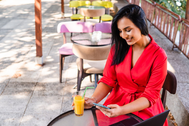 一位年轻的女商人正在一家花园咖啡馆里使用手机图片下载