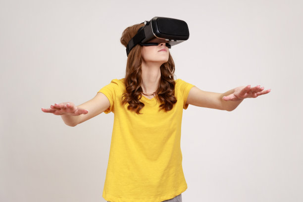 少女肖像与虚拟现实眼镜玩游戏模拟器，伸出手，触摸物体在网络空间。图片下载