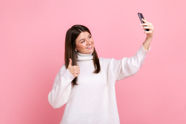 快乐积极微笑的年轻成年女性直播，向关注者竖起大拇指。图片下载