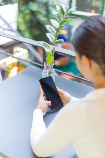 在特内里费市的一家咖啡馆里，一名年轻的西班牙裔女子正在使用她的智能手机图片下载