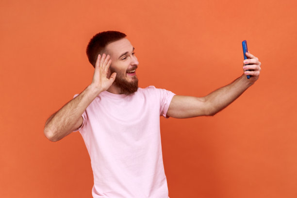 一名男子在视频通话中打着招呼手势，用手机进行在线交谈。图片下载