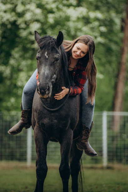 微笑的年轻女子长头发骑着马在牧场的树图片下载