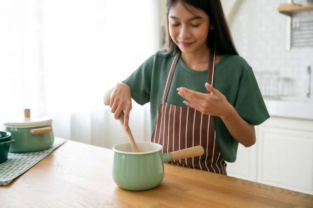 年轻美丽的亚洲女人在家里厨房做饭图片下载