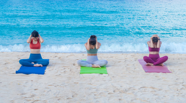 一群穿着运动服的妇女在沙滩上练习瑜伽地图。瑜伽是一种冥想和健康的运动，在夏日的蓝天碧海中放松身心图片下载