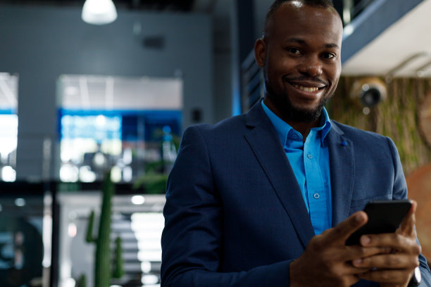 快乐的商人穿着西装在办公室使用智能手机图片下载