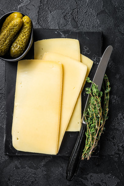 新鲜的生Raclette瑞士奶酪切片大理石板。黑色背景。俯视图图片下载