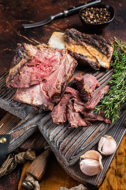 木砧板上的百里香焖小牛肉。黑暗的背景。俯视图图片下载