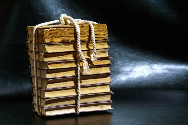 用绳子系在黑色背景上的一摞旧书图片下载
