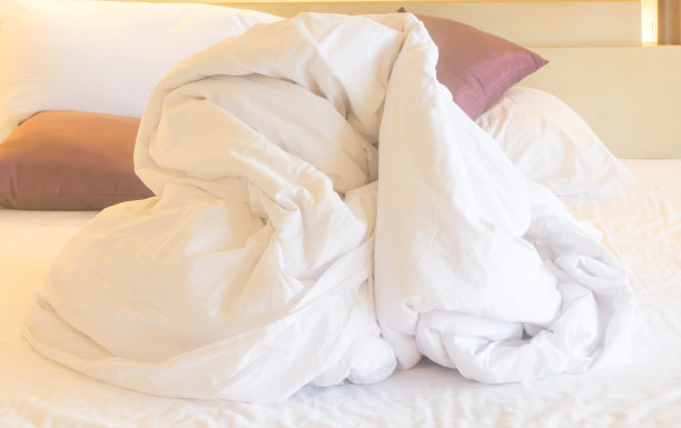酒店房间内白色毛毯及其他被褥因客人过夜使用而不整洁，近照图片下载