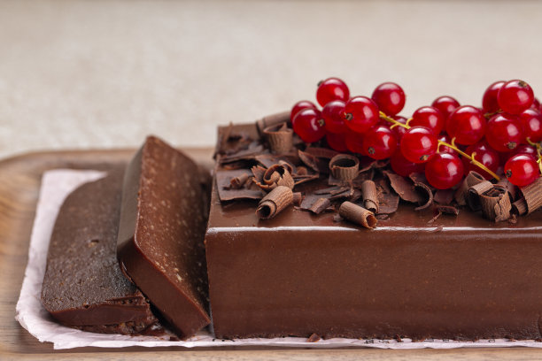 切片巧克力布丁蛋糕，用明胶和杏仁制成的奶油冻，没有烘焙甜点，用红醋栗装饰。特写镜头。图片下载