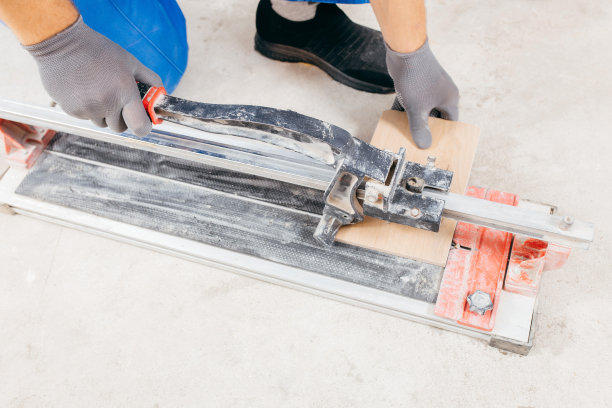 修理工的手在地板上的瓷砖切割机上切割瓷砖。近距离图片下载