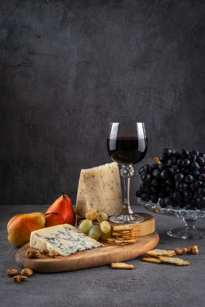 一杯红酒，蓝色的奶酪和葡萄在黑色的背景。红酒配奶酪和水果。空间的文本图片下载