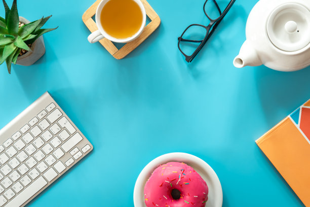 甜甜圈，茶和键盘在一个蓝色的背景，平铺。图片下载