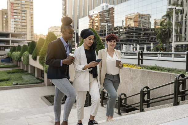 多种族、不同年龄的成功职场女性团队。女商人走在城市的外面。以建筑为背景，领导理念图片下载