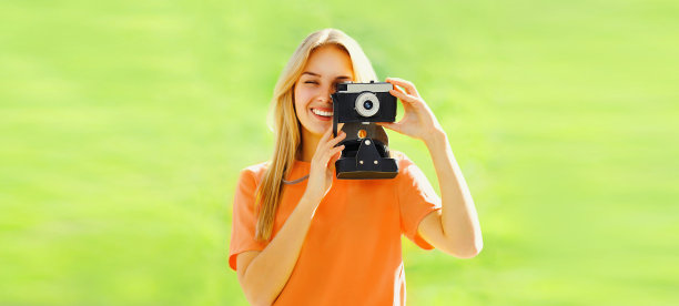 快乐的年轻女子摄影师肖像与胶片相机在夏季公园图片下载