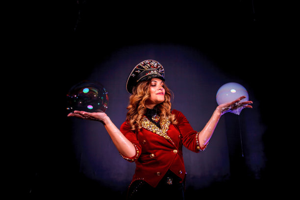 女魔术师魔术师马戏团表演肥皂泡泡表演在戏剧服装时尚的帽子在黑色的背景。穿着舞台服装的女演员。剧场表演的概念。复制文本空间图片下载
