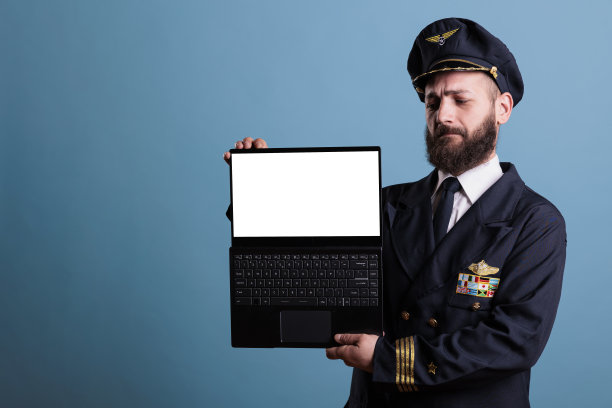 严肃的飞行员用白色屏幕显示笔记本电脑图片下载