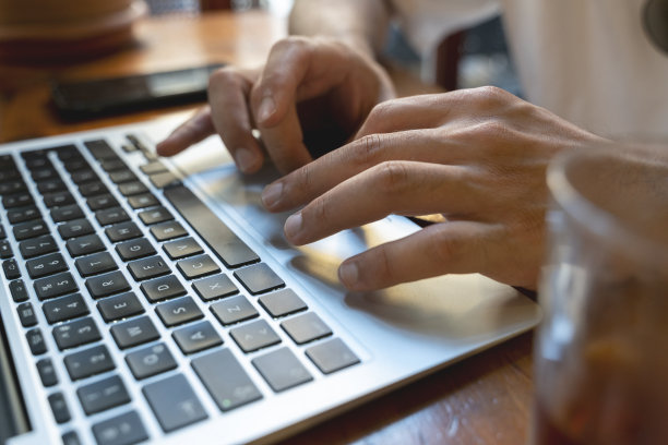 在笔记本电脑上打字的手的特写。夜间工作的概念。库存图片图片下载