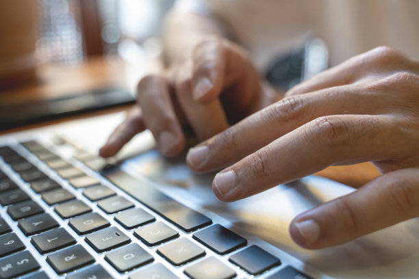 在笔记本电脑上打字的手的特写。夜间工作的概念。库存图片图片下载