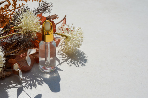 秋天的化妆品，琥珀色的玻璃滴管瓶在cosncrte背景与干燥的花和叶。秋天的成分图片下载