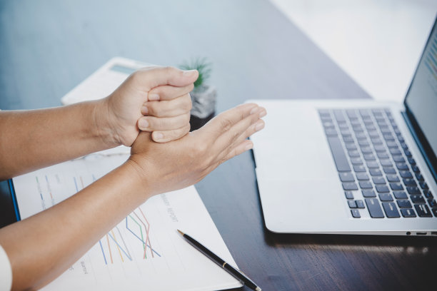 关节炎患者，手指妇女因在办公室工作而疼痛。概念办公室综合征手痛源于职业病，女性因使用笔记本电脑而手腕痛，手腕痛。图片下载