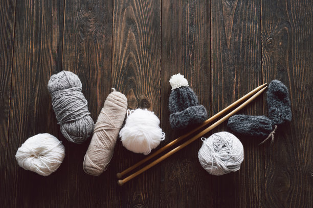毛线球，针织小帽子和木制的针织针在木制的背景图片下载