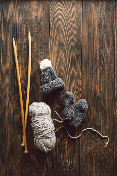 毛线球，针织小帽子和木制的针织针在木制的背景图片下载
