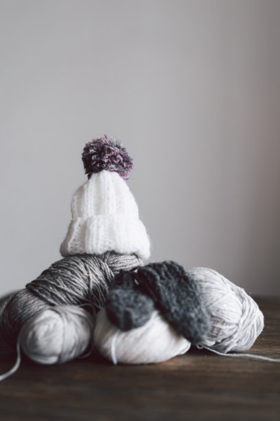 毛线球，针织小帽子和木制的针织针在木制的背景图片下载