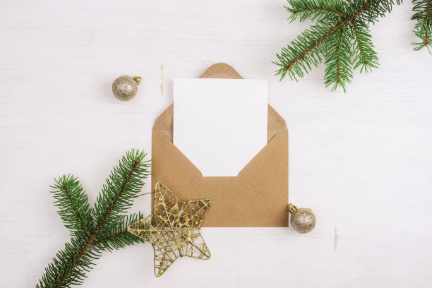 打开棕色信封与空白白色卡片和圣诞装饰白色木桌。俯视图，平铺，模型图片下载