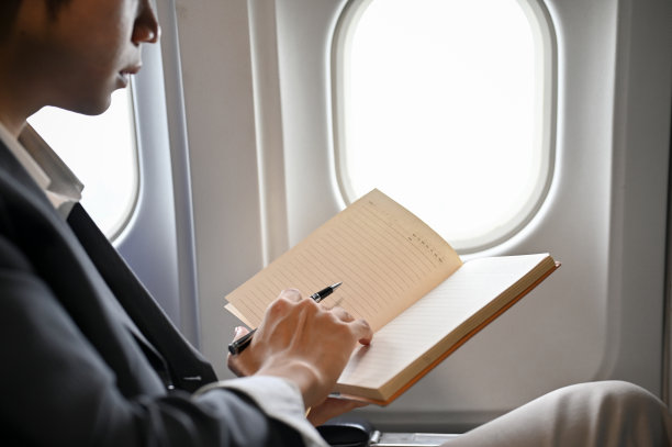 精明的亚洲商人正在飞机上，在笔记本或日记本上查看行程。裁剪图片下载