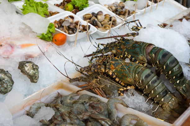 在泰国夜市，蓝色龙虾，对虾，不同类型的贻贝，蛤蜊或贝壳在冰上的选择性聚焦照片图片下载
