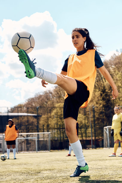 足球运动员在场上进行运动训练时踢球。图片下载